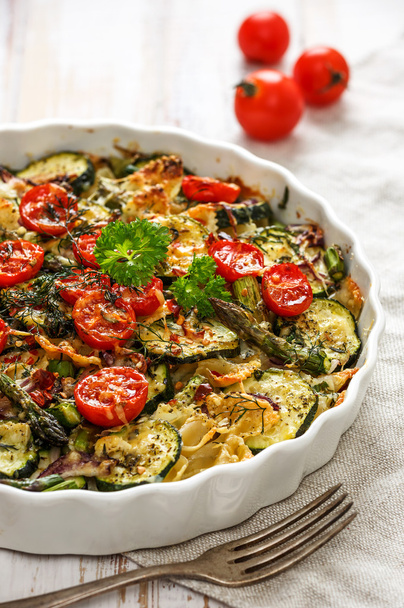 Casseruola vegetariana con pasta, zucchine, pomodorini, asparagi e cipolle
 - Foto, immagini