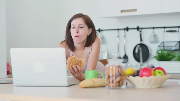 Mujer come hamburguesa y trabaja con el ordenador portátil
 - Imágenes, Vídeo