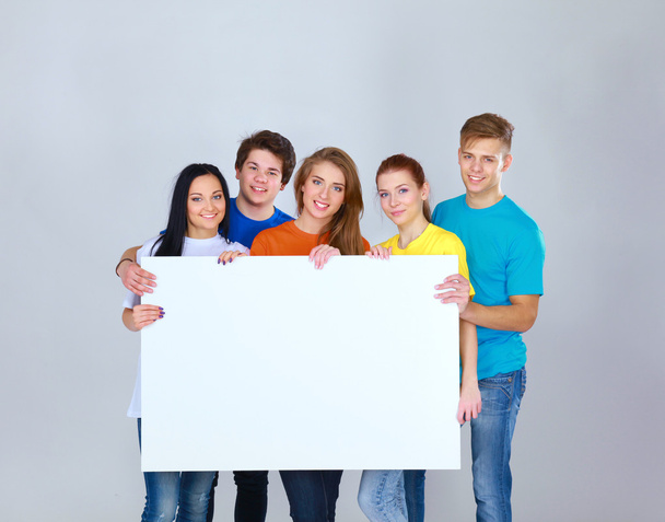 Group of young friends holding a blank board, isolated on white background - Фото, зображення