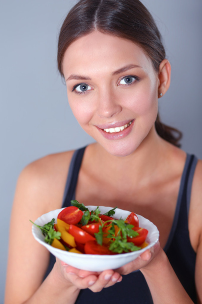 Vejetaryen sebze salatasıyla gülümseyen genç bir kadının portresi. - Fotoğraf, Görsel