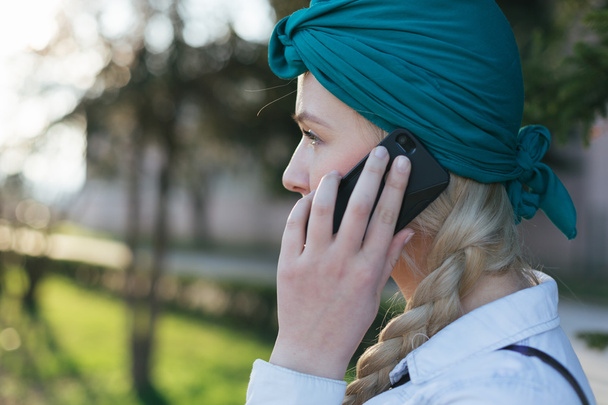 Pretty young Caucasian woman with backpack speaking on the phone - Photo, Image