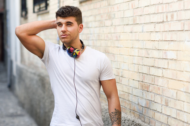 Молодий чоловік у міському фоні слухає музику з навушниками
 - Фото, зображення
