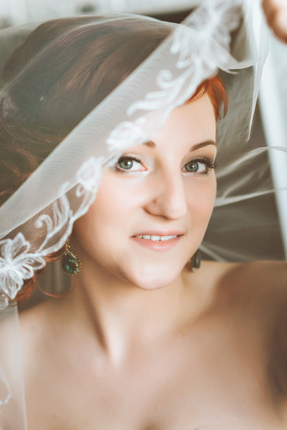 Portrait of young redheaded woman bride, through the wedding veil. Looking at  camera - 写真・画像