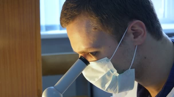 Um close de um técnico de laboratório, médico, biólogo ou cientista olhando através de um microscópio
 - Filmagem, Vídeo