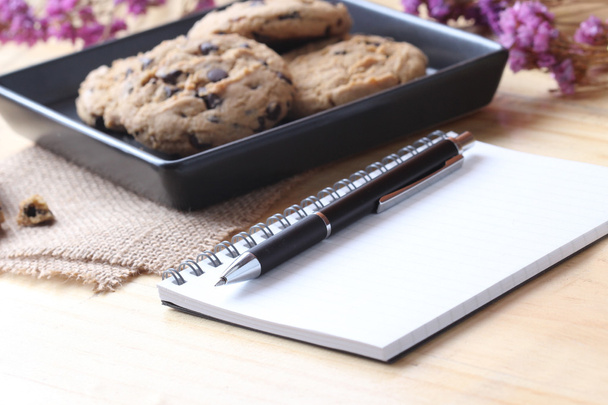 biscotti con gocce di cioccolato con penna e notebook
 - Foto, immagini