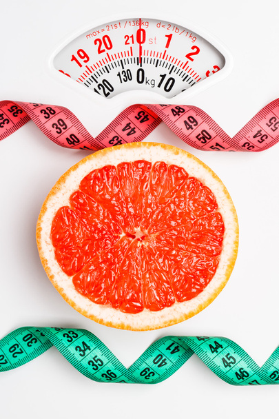 Grapefruit with measuring tape on weight scale. Dieting - Photo, Image