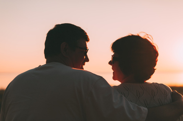 Adult couple embracing at sunset and sea. - Valokuva, kuva