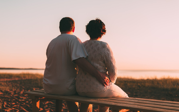 Adult couple embracing at sunset and sea. - Фото, зображення