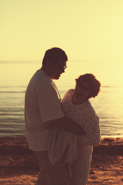 Volwassen paar omarmen bij zonsondergang en zee. - Foto, afbeelding
