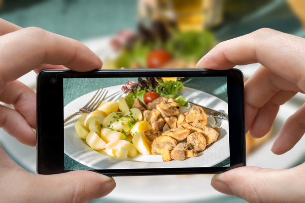 Man is photographing meal in restaurant with smartphone. - Фото, зображення