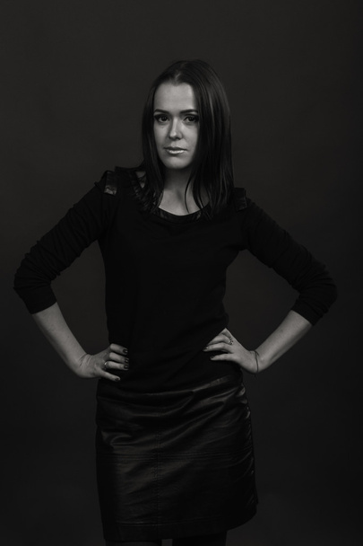 Beautiful, mysterious, cute brunette on a dark background. Black and white photo Beautiful mysterious brunette. - Zdjęcie, obraz