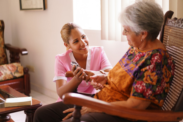 Hospice sairaanhoitaja auttaa vanha nainen matkapuhelimella
 - Valokuva, kuva