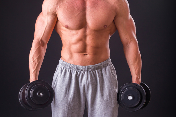 Bodybuilder posieren in verschiedenen Posen und demonstrieren ihre Muskeln. Scheitern auf dunklem Hintergrund. Männchen mit angespannten Muskeln. schöner muskulöser Körper Athlet. - Foto, Bild