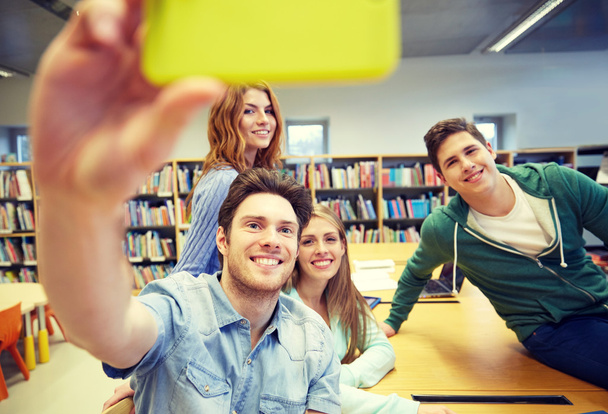 students with smartphone taking selfie in library - Photo, image