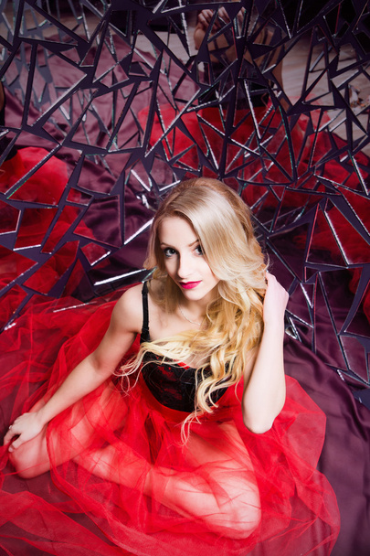 beautiful blond girl wearing a corset and red skirt in a mirror  - Photo, Image