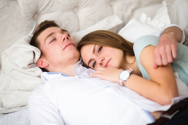 Fiatal szerelmes pár az ágyban. A fiú vállára kislányt - Fotó, kép