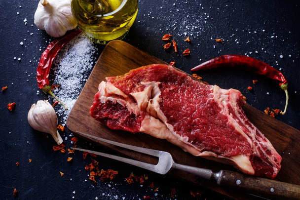 Raw meat steak entrecote on the cutting board with spice on the  - Фото, изображение