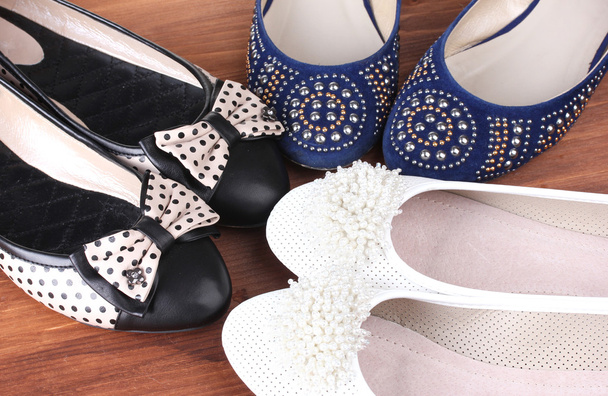 Several pairs of female flat shoes on wooden background - 写真・画像