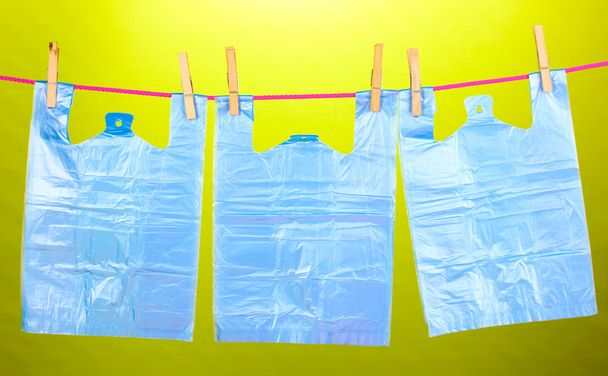 Cellophane bags hanging on rope on green background - Фото, зображення