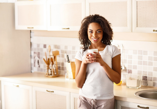 Pleasant girl drinking tea in the kitchen - Photo, Image
