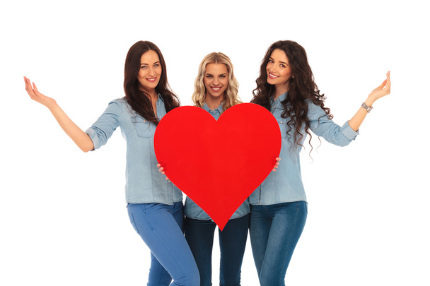três mulheres casuais sorridentes dando boas-vindas ao seu coração
 - Foto, Imagem