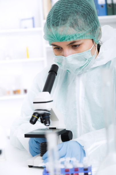 Γυναίκα που εργάζεται με ένα μικροσκόπιο σε ένα εργαστήριο. Τόνωση της εικόνας - Φωτογραφία, εικόνα