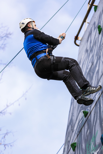 Homme grimpant un mur dans un exercice d'alpinisme
 - Photo, image