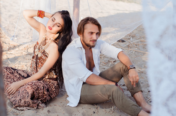 beautiful young couple sitting on the sand on the beach in woode - Фото, зображення