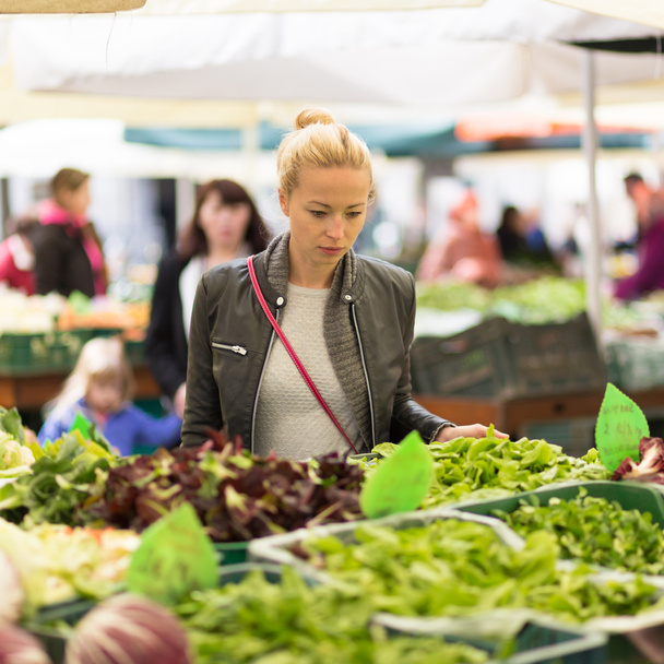 地元の食品市場で野菜を買う女性. - 写真・画像