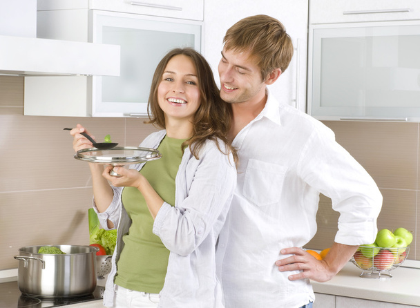 Young happy couple cooking together at home kitchen - Fotó, kép