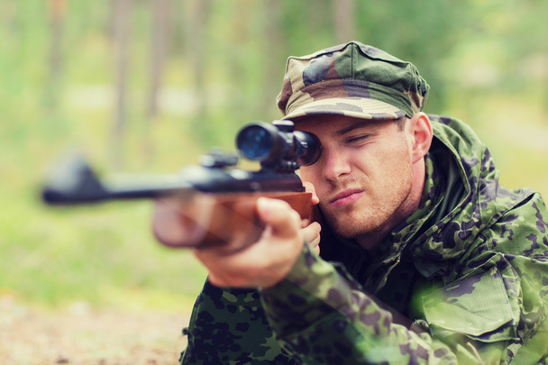 young soldier or hunter with gun in forest - Photo, image