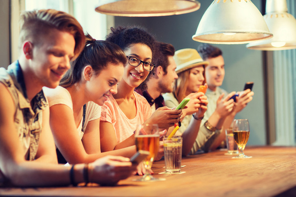 happy friends with smartphones and drinks at bar - Foto, Imagem