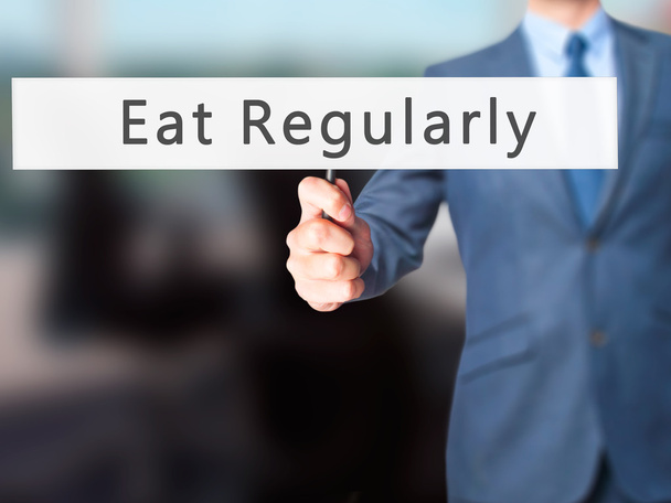 Їжте регулярно - рука бізнесмена тримає знак
 - Фото, зображення