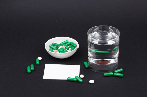 таблетки зі склянкою води, щоб пити таблетки на темно-чорному тлі. Біль
 - Фото, зображення