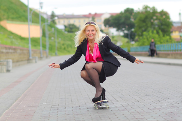 Zakenvrouw op een skateboard buitenshuis - Foto, afbeelding