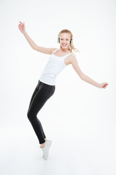 Cheerful woman in yellow headphones listening to music and dancing - Foto, Imagem