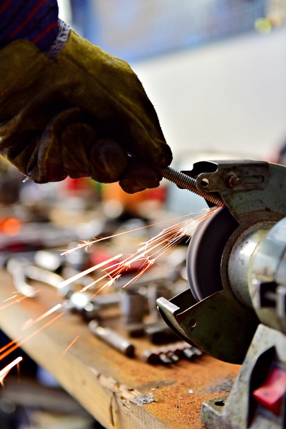 Mechanic polishing a screw on industrial polishing machine - Foto, Bild