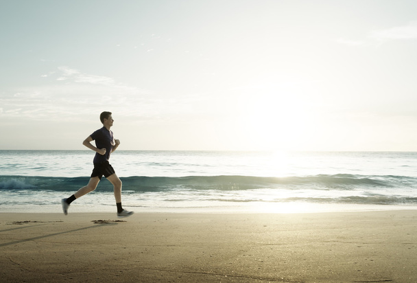 Чоловік біжить на тропічному пляжі на заході сонця
 - Фото, зображення