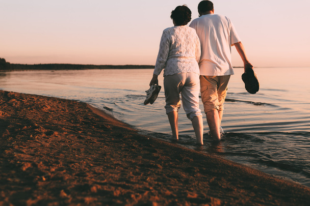 Adult couple walks on the seashore. - Фото, зображення