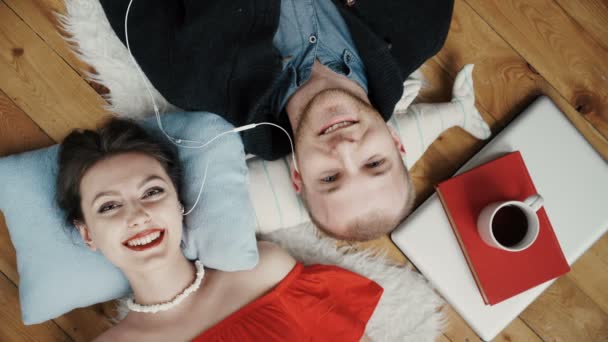 Teenager couple listening to music with headphones on a carpet - Materiał filmowy, wideo