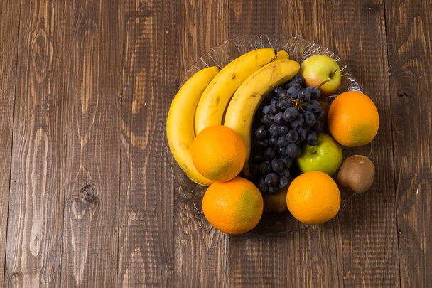 Grapes, oranges, bananas, kiwi and apples are in dish - Фото, изображение