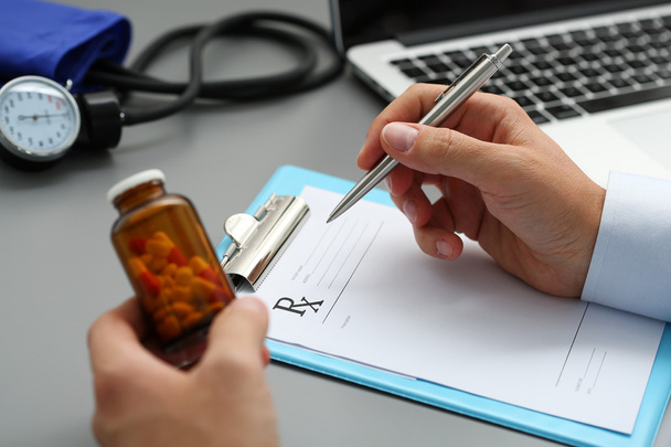 Male medicine doctor hand hold jar of pills and write prescripti - Photo, Image