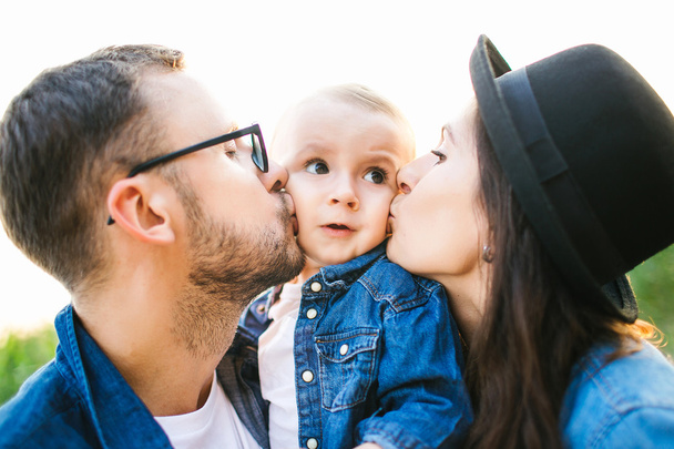 Young hipster father mother kissing cute baby in corn field - Foto, Imagen
