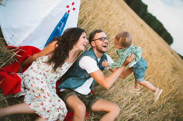 Young hipster father, mother cute baby son on picnic - Фото, изображение