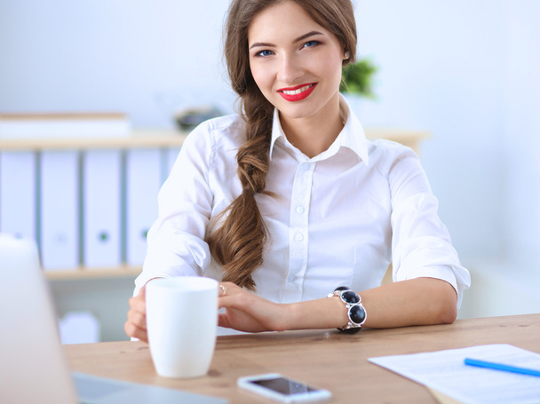 Attractive businesswoman sitting  on desk in the office - Fotoğraf, Görsel