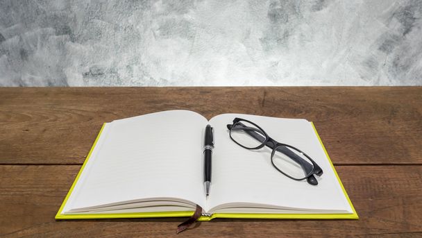 Caderno em branco com caneta e óculos na mesa de madeira
. - Foto, Imagem
