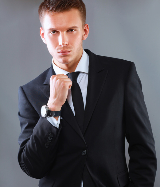 灰色の背景上に分離されて立っている若いビジネスの成功の男のポートレート - 写真・画像
