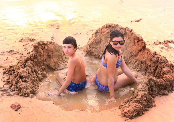10 代の少年と少女は、ビーチで砂で遊ぶ - 写真・画像