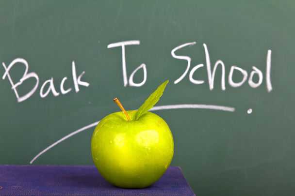 Back to school written on chalkboard with green apple and books - Foto, Imagen