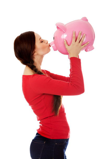 Happy young woman kissing a piggybank - Φωτογραφία, εικόνα